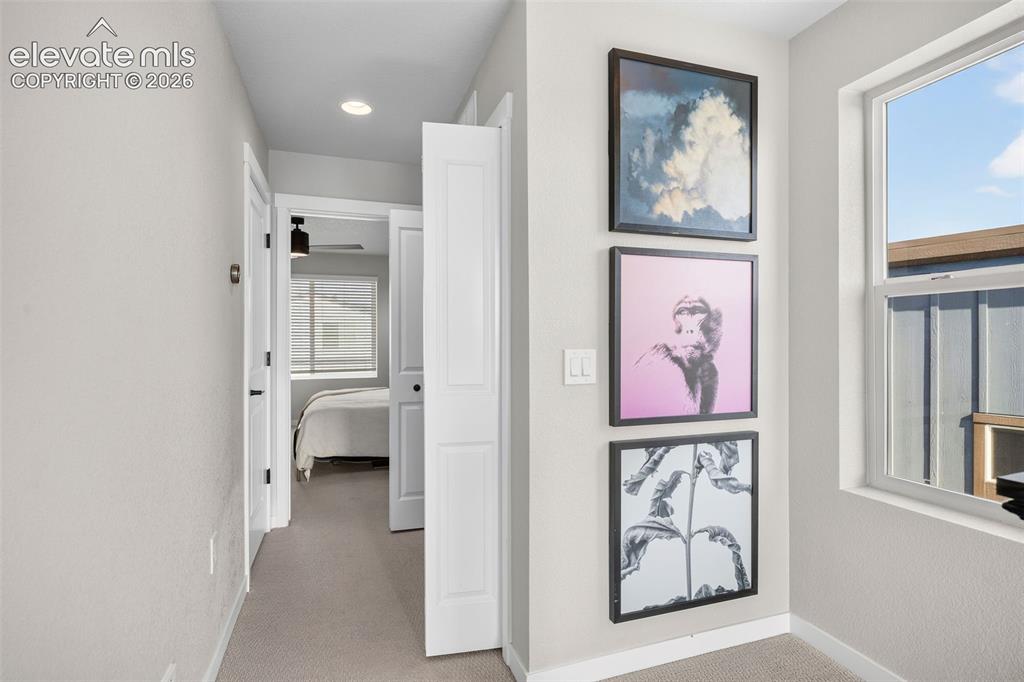 Image 23 of 48: Upstairs, the hallway bright with an oversized window. The primary suite is