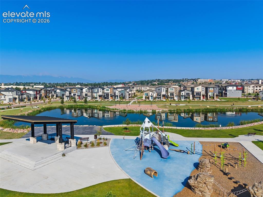 Image 43 of 48: View of the playground and pavilion with the pond at the neighborhood park 