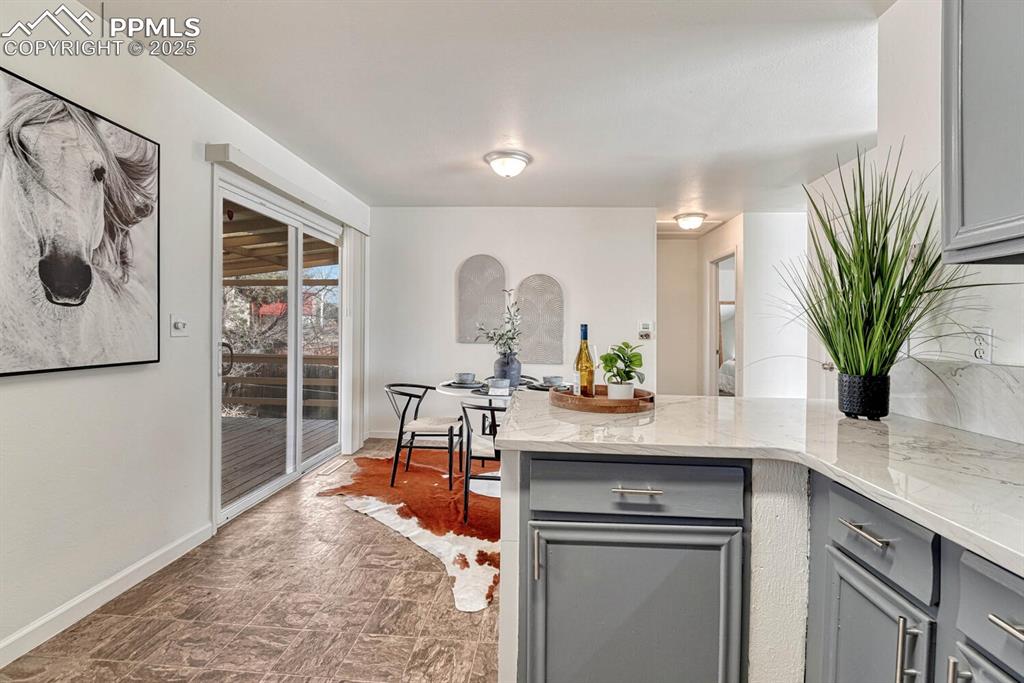 Image 11 of 43: Kitchen with gray cabinets, a peninsula, and light stone countertops