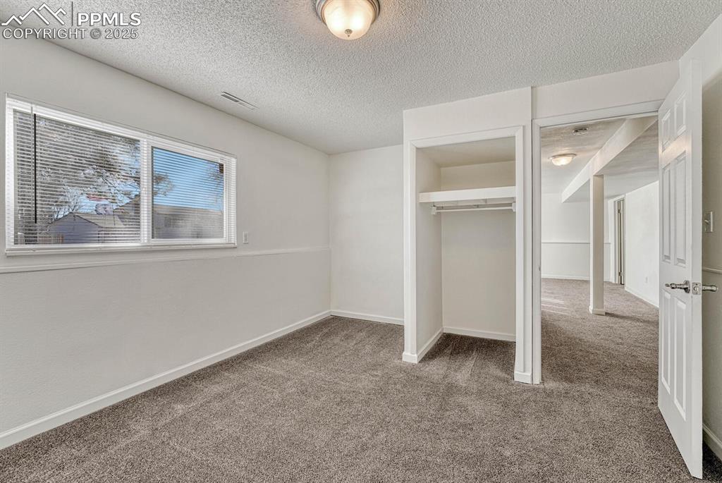 Image 29 of 43: Unfurnished bedroom with carpet, a textured ceiling, and a closet