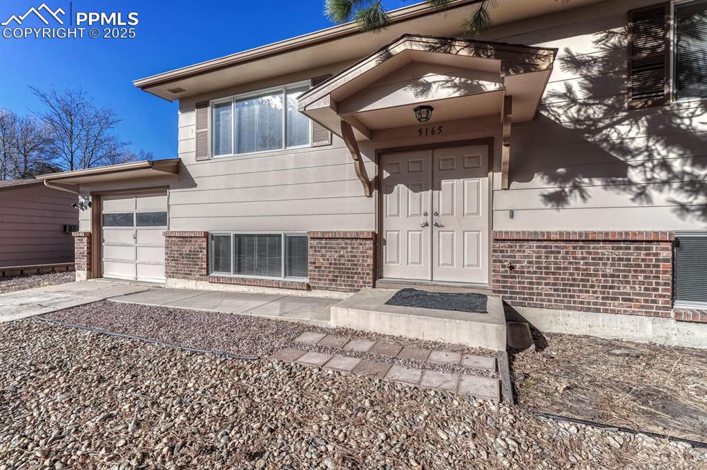 Image 3 of 43: Entrance to property featuring concrete driveway, a garage, and brick sidin