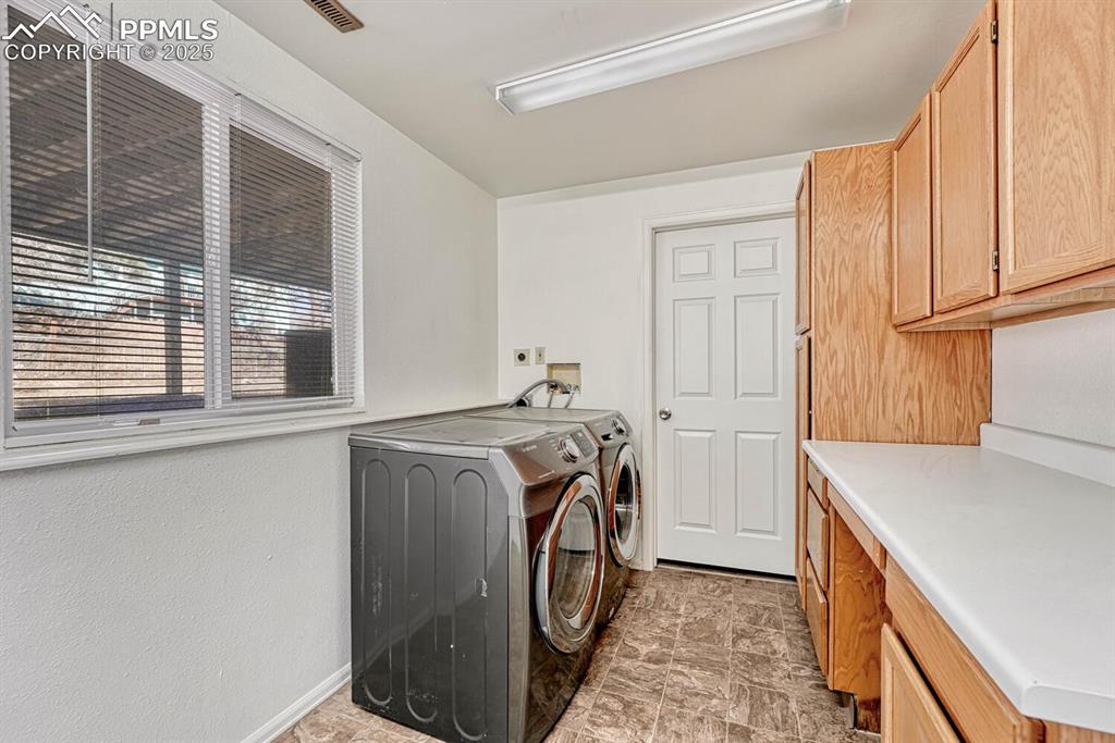 Image 33 of 43: Washroom with washer and dryer, cabinet space, and stone finish floors