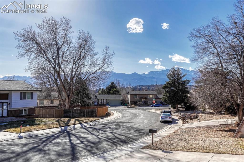 Image 42 of 43: View of asphalt road with curbs, a mountain view, and sidewalks