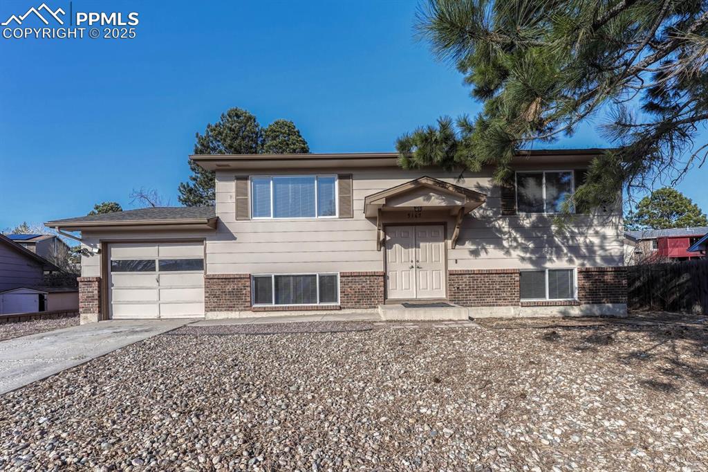Image 43 of 43: Bi-level home featuring an attached garage, brick siding, and driveway