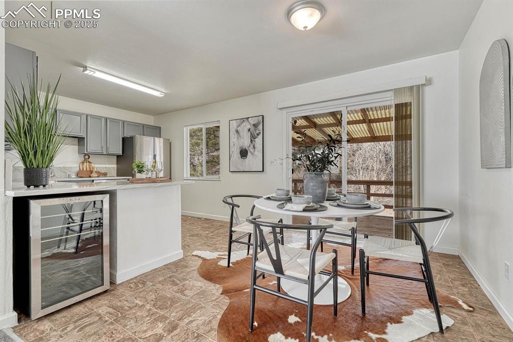 Image 9 of 43: Dining space featuring beverage cooler and stone finish flooring