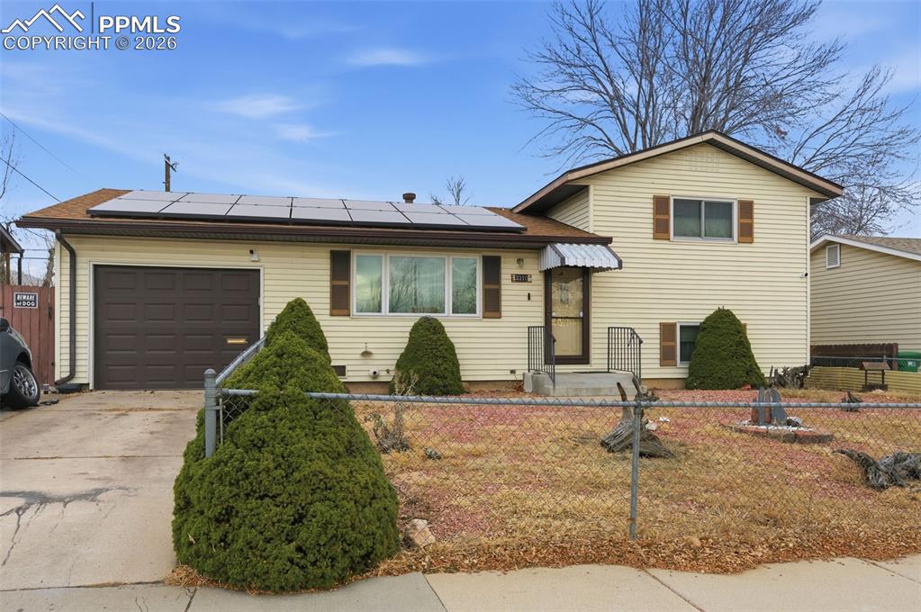Image 1 of 24: Split-level residence featuring light-colored siding, a prominent front-fac