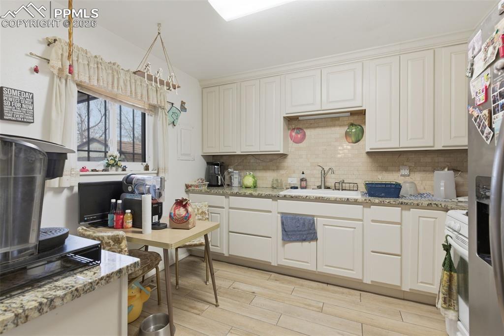 Image 10 of 24: Kitchen featuring light-toned cabinetry, a subway tile backsplash, and wood