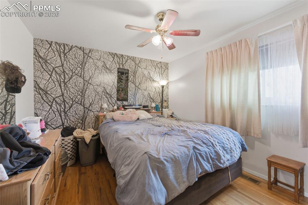 Image 13 of 24: Room featuring an accent wall with a tree branch pattern, wood-finish floor