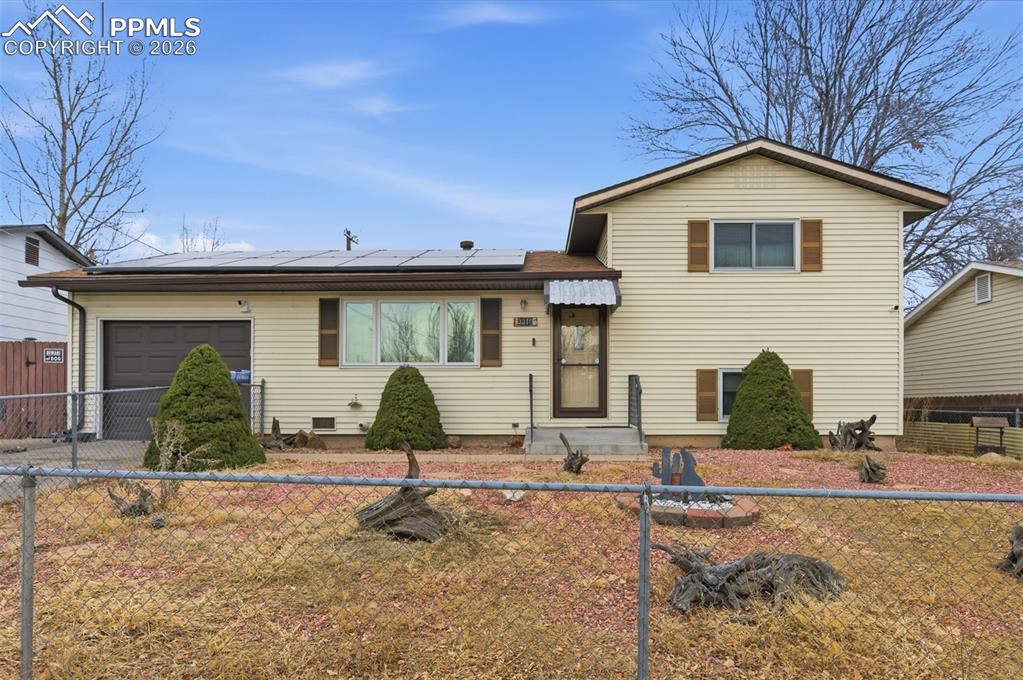 Image 2 of 24: Split-level home featuring light-colored siding and brown trim accents
