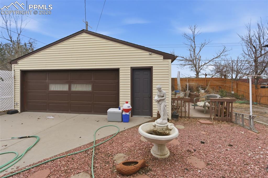 Image 21 of 24: Detached garage featuring horizontal siding, a brown panel garage door with