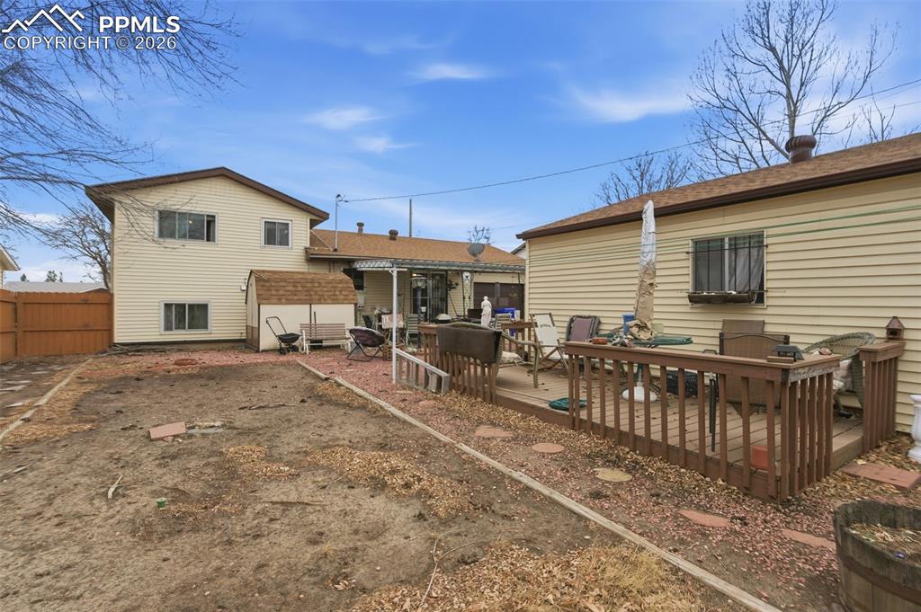 Image 23 of 24: Rear exterior featuring a spacious wooden deck with railings, a detached ut