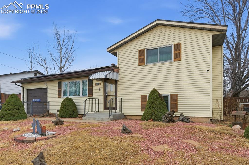 Image 3 of 24: Split-level exterior featuring light-colored siding, a covered entry, and a