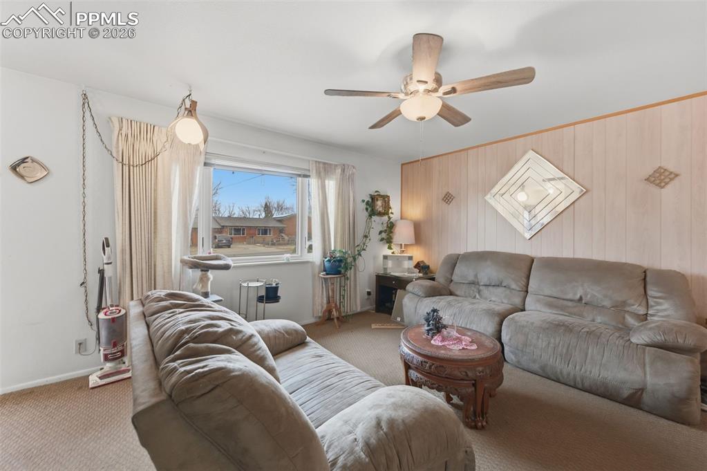 Image 8 of 24: Carpeted living area featuring a ceiling fan with integrated lighting, a la