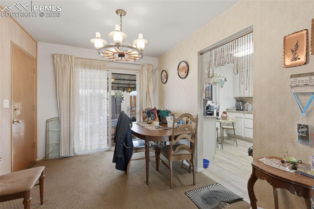 Image 9 of 24: Dining area featuring a wagon wheel style chandelier, carpet flooring, and 