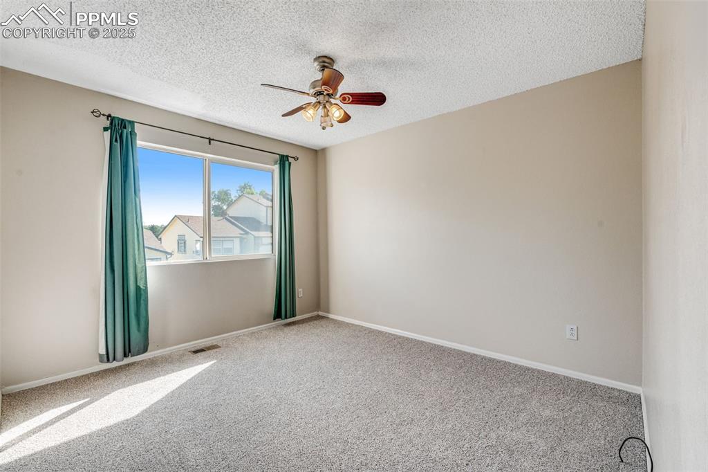 Image 17 of 30: Second bedroom featuring ceiling fan and a textured ceiling