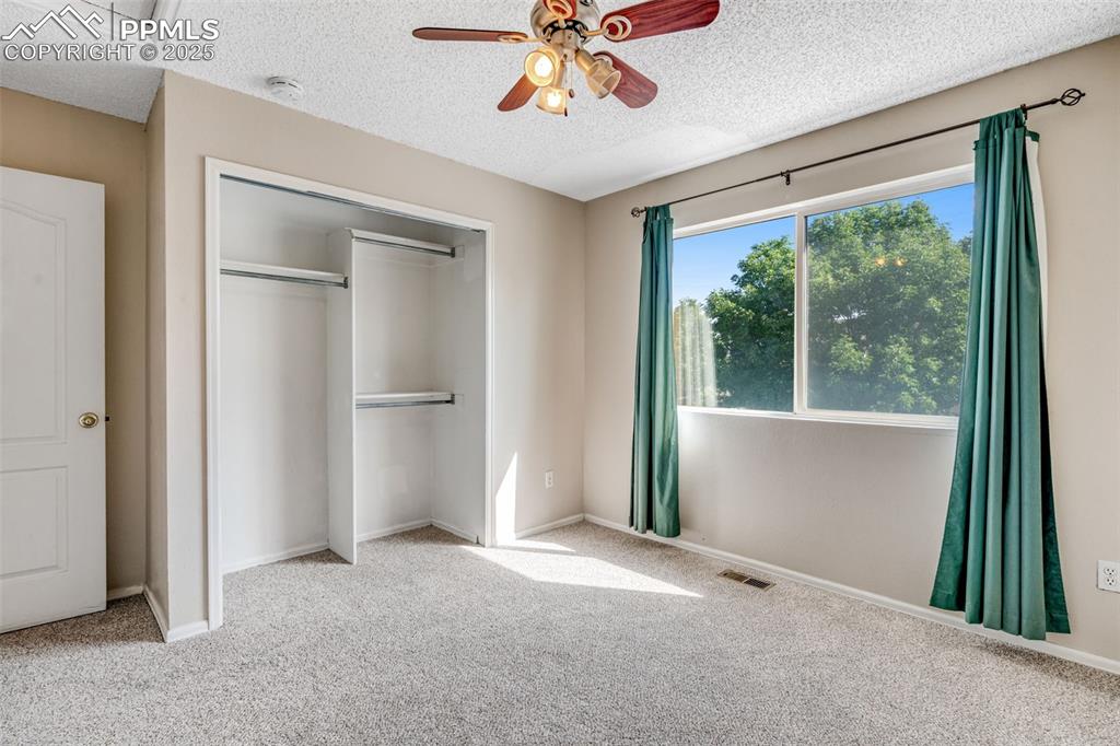 Image 18 of 30: Second bedroom featuring carpet flooring, a ceiling fan, and a closet
