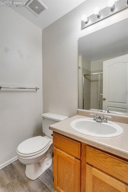 Image 19 of 30: Full bath with a textured wall, a shower stall, vanity, and light wood-styl