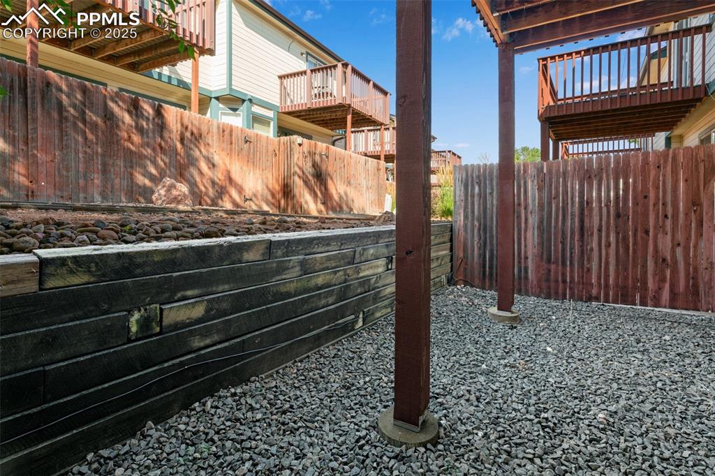 Image 22 of 30: Fenced backyard with a balcony