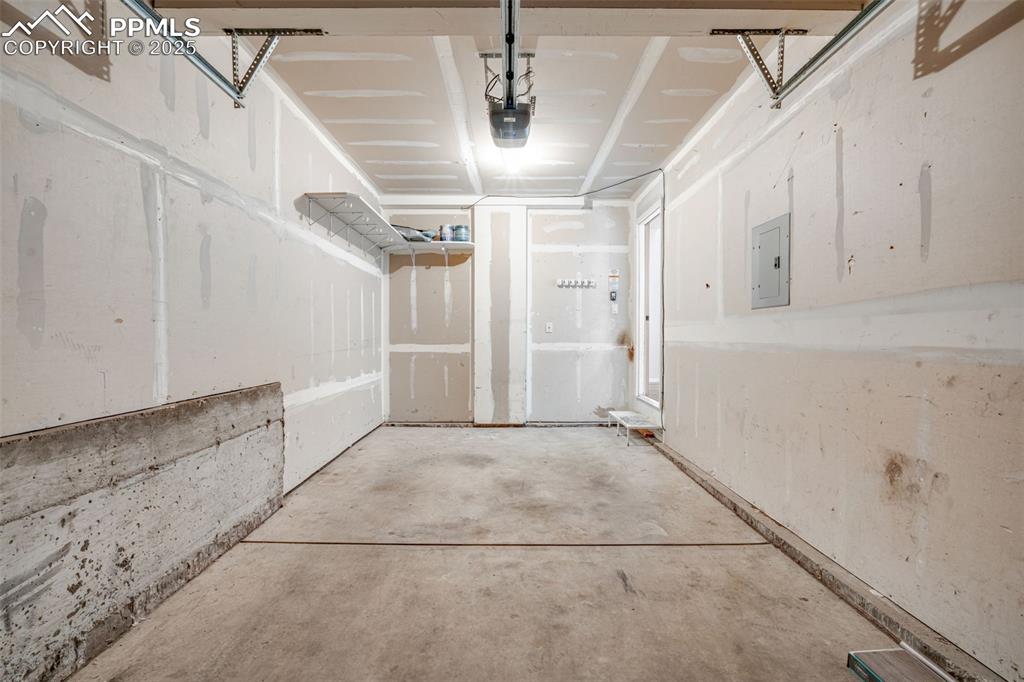 Image 25 of 30: Garage with electric panel and a garage door opener