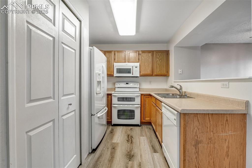 Image 3 of 30: Kitchen with white appliances, light countertops, light wood-style floors,