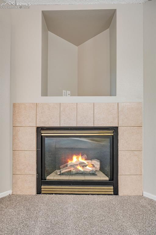 Image 7 of 30: Detailed view of a tile fireplace and carpet flooring