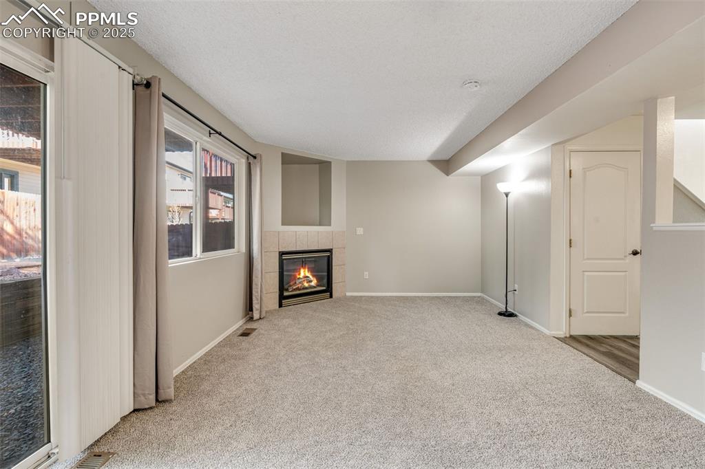 Image 8 of 30: Unfurnished living room featuring carpet, a fireplace, and a textured ceili