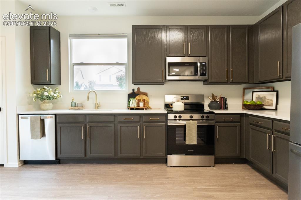 Image 7 of 26: Kitchen featuring dark wood-finish cabinetry with gold-tone hardware, quart