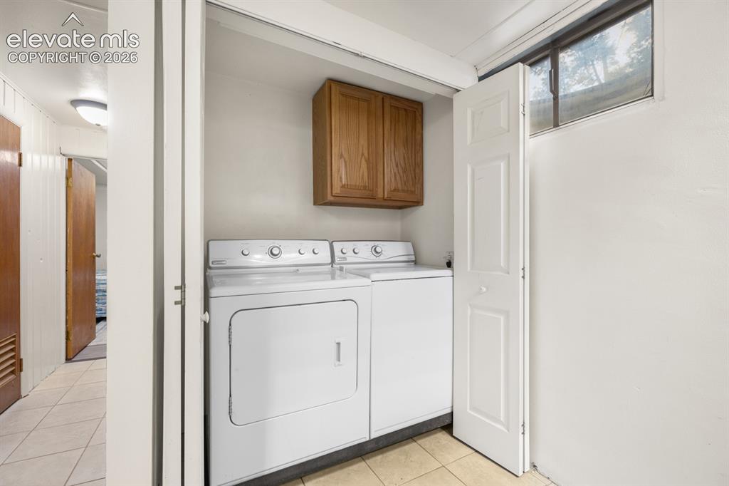 Image 18 of 32: Dedicated laundry area with upper cabinet and a window for natural light