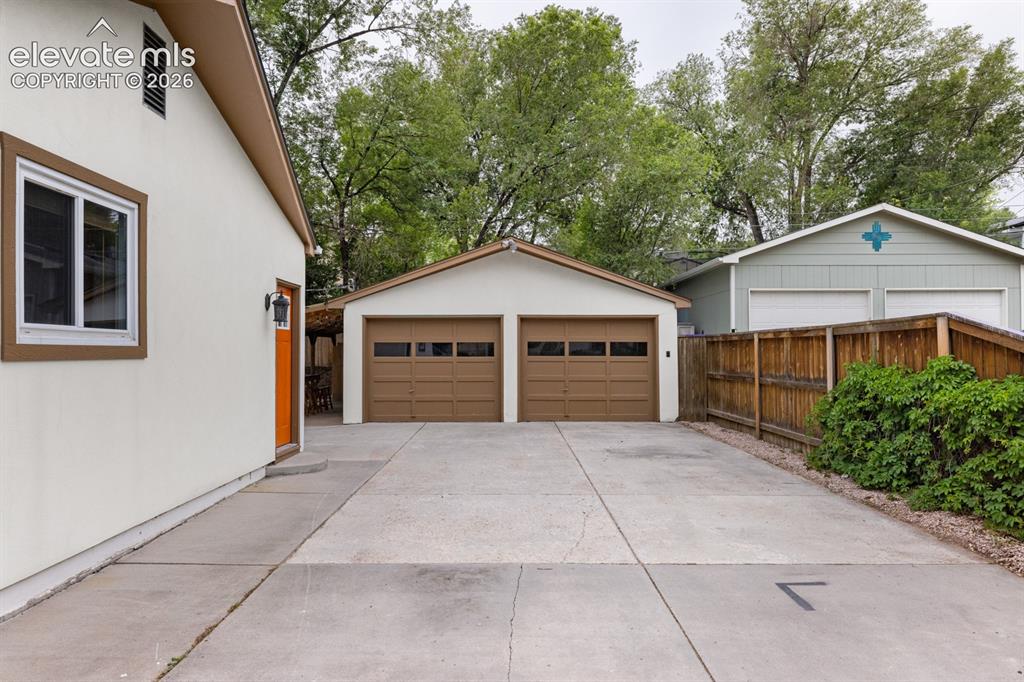 Image 2 of 32: Wide concrete driveway leading to the oversized two-car garage with workben