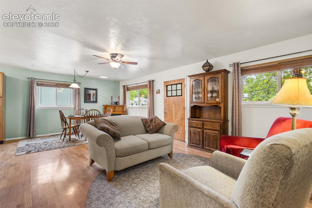 Image 3 of 32: Spacious living area featuring wood-finish flooring, multiple windows, and