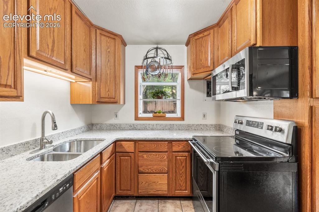 Image 4 of 32: Kitchen with oak cabinetry, granite countertops, stainless steel double bas