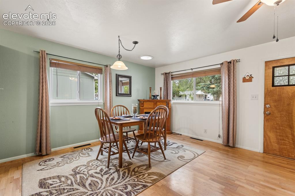 Image 6 of 32: Dining area featuring wood-finish floorin and two large windows with wood b