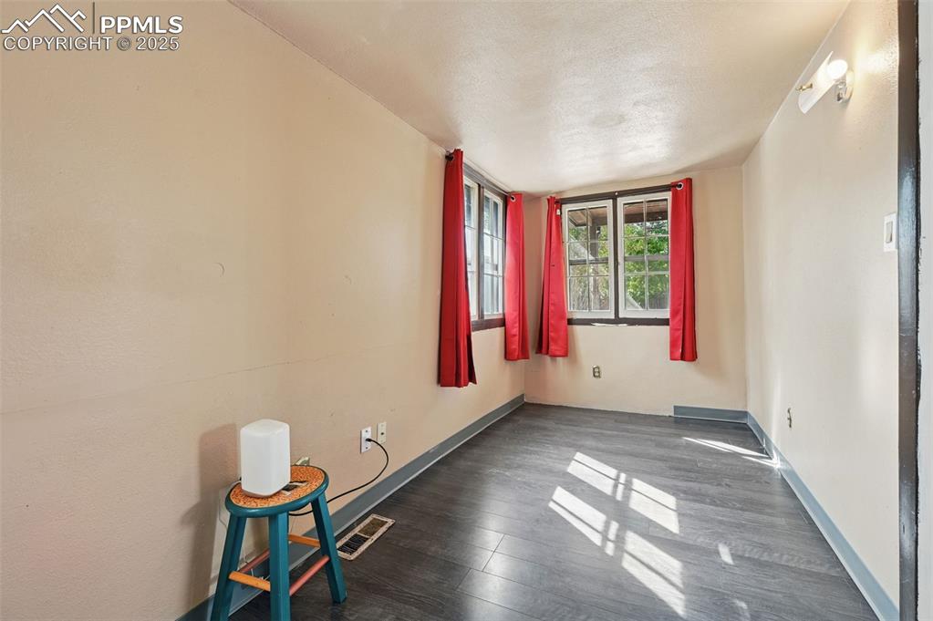 Image 13 of 24: Empty room featuring dark wood-type flooring and a textured ceiling
