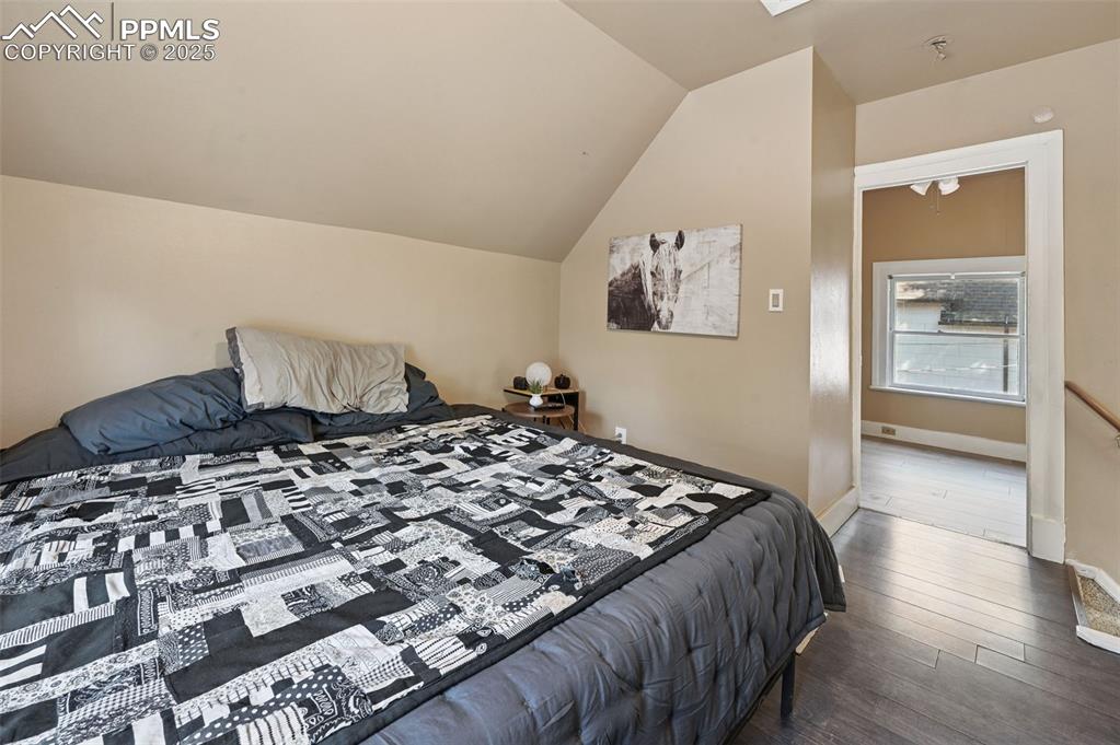 Image 18 of 24: Bedroom featuring dark wood finished floors and lofted ceiling
