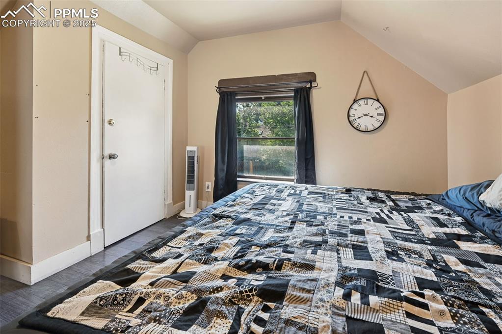 Image 21 of 24: Bedroom with lofted ceiling and wood finished floors