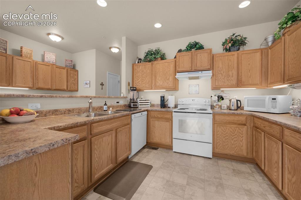 Image 11 of 28: Kitchen featuring light wood cabinetry, stone-look laminate countertops, an