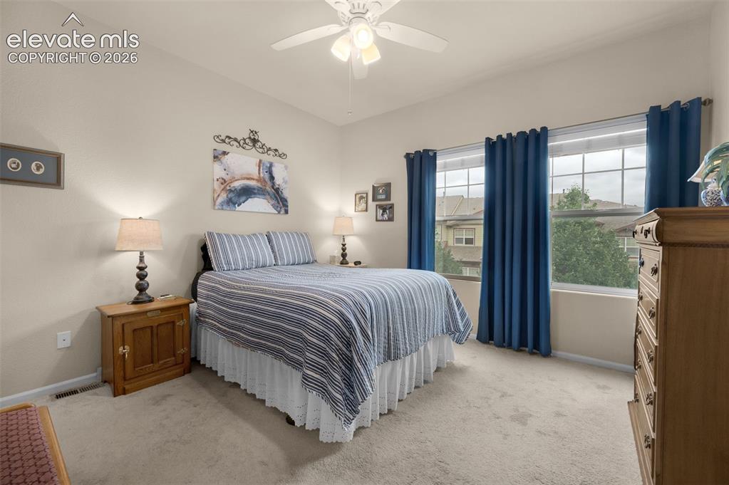 Image 16 of 28: Carpeted bedroom with a vaulted ceiling and a pair of large windows, and ne