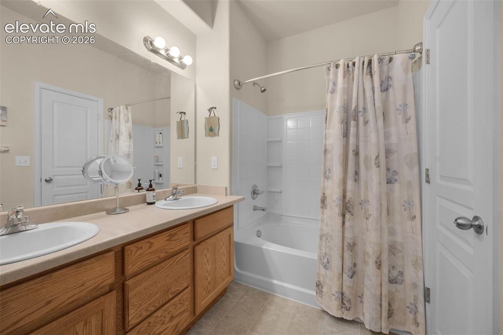 Image 17 of 28: Dual basin vanity with wood-finish cabinetry, a large wall-mounted mirror,
