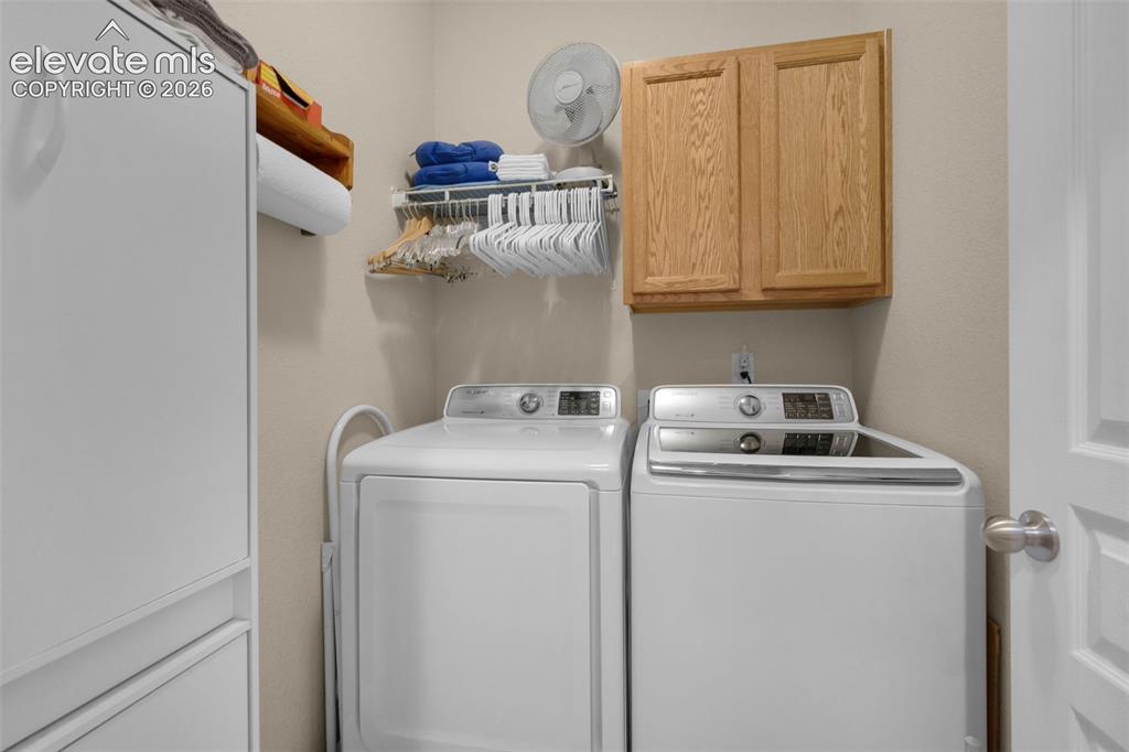 Image 18 of 28: Dedicated laundry area featuring light-toned walls, built-in wooden cabinet