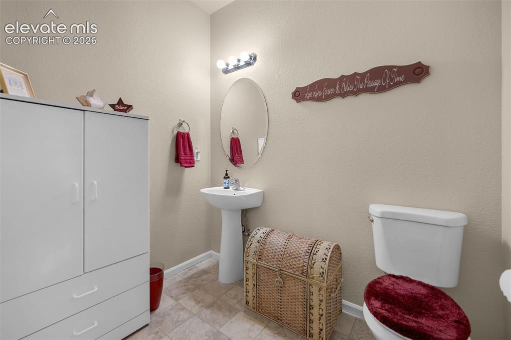 Image 5 of 28: 1/2 bath off the living Room with a pedestal sink with an oval mirror, over