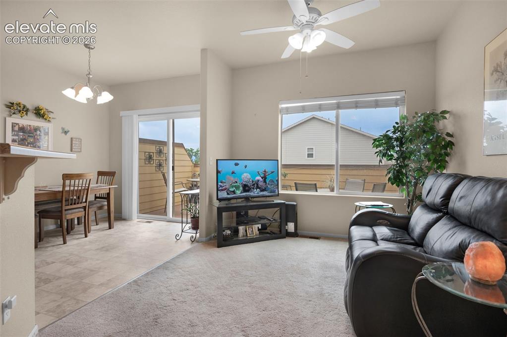 Image 7 of 28: Open-concept living area featuring a ceiling fan with integrated lighting,