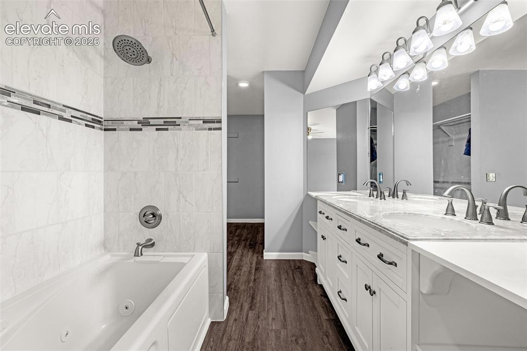 Image 17 of 49: Bathroom featuring a jetted tub with tiled surround and shower fixture, a d