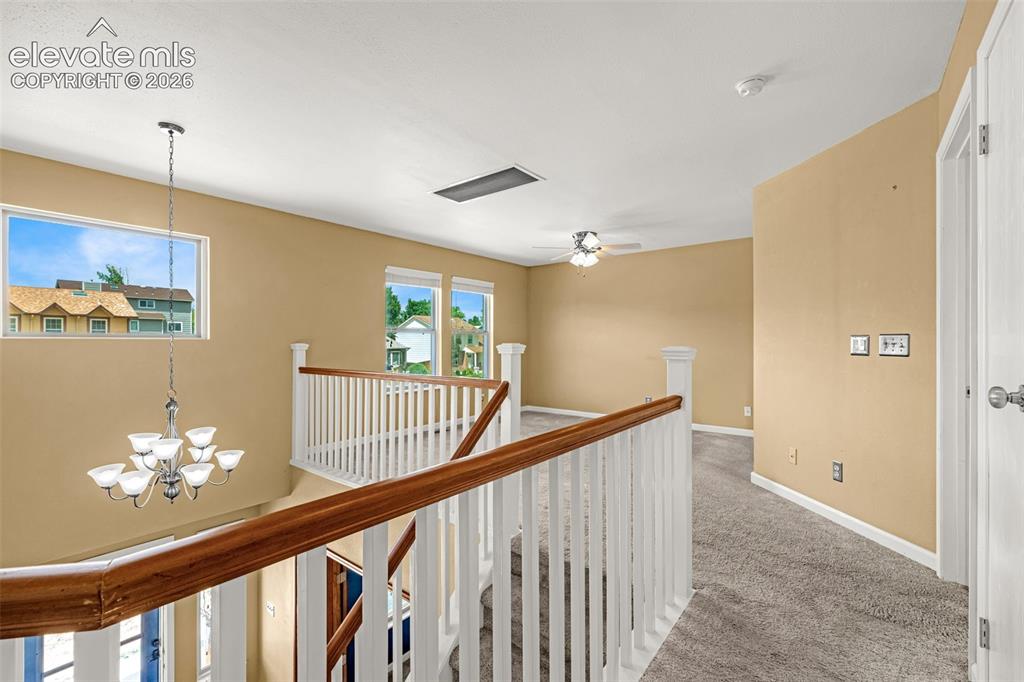 Image 19 of 49: Upper-level landing featuring a wood and white spindle staircase railing