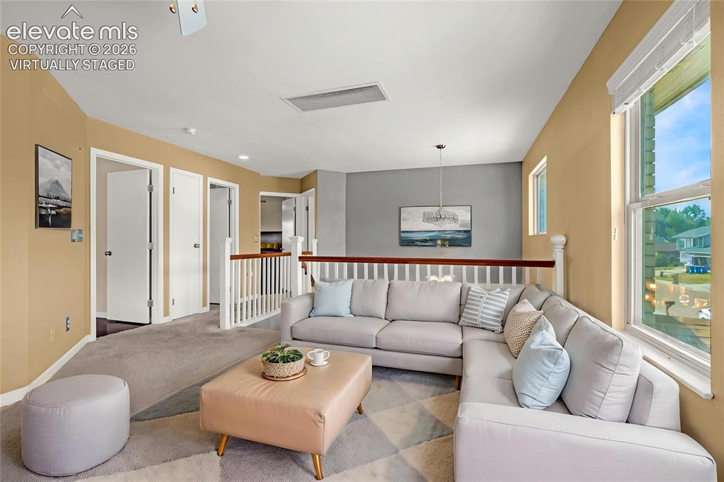 Image 20 of 49: Carpeted upstairs landing featuring a white balustrade with a wood-finish h
