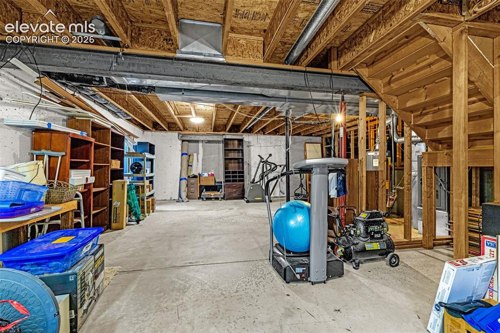 Image 25 of 49: Unfinished basement space featuring exposed wood framing, concrete flooring
