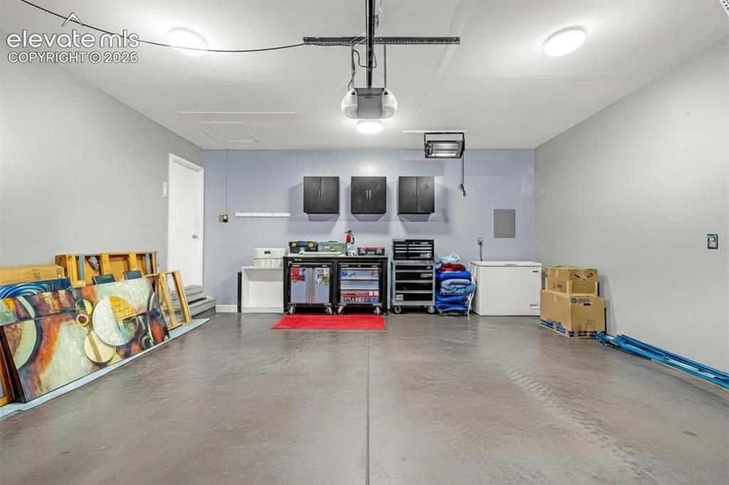 Image 26 of 49: Spacious garage with light grey walls, concrete flooring, and overhead ligh