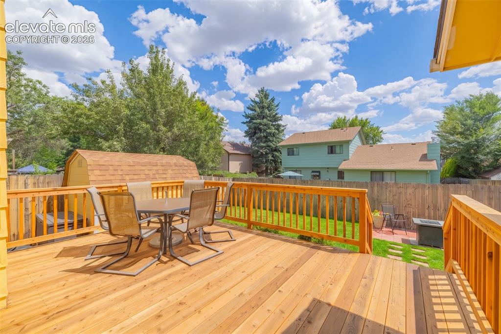 Image 29 of 49: Spacious wood deck with full railing and steps to the yard, featuring a sto