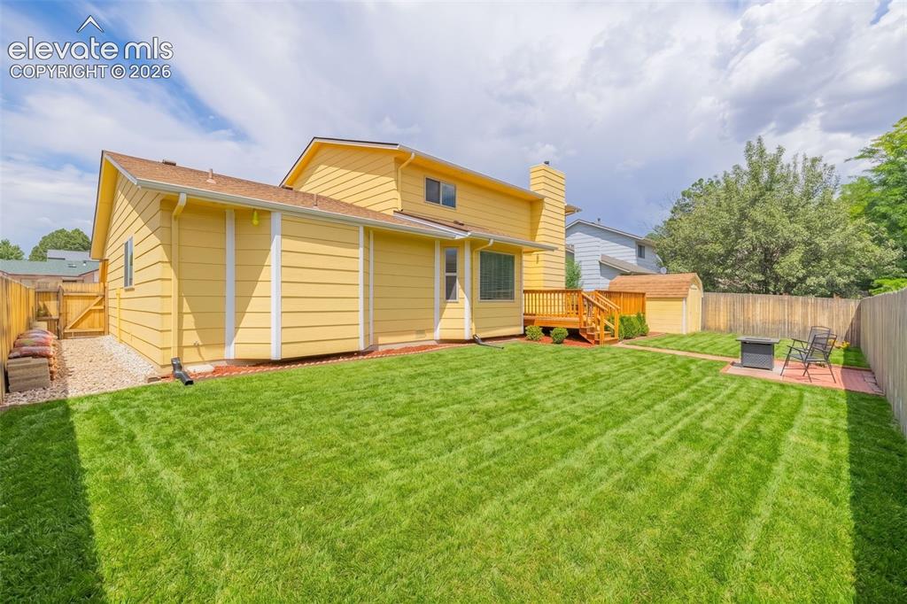 Image 31 of 49: Spacious backyard featuring a manicured lawn, wood privacy fencing, and a m
