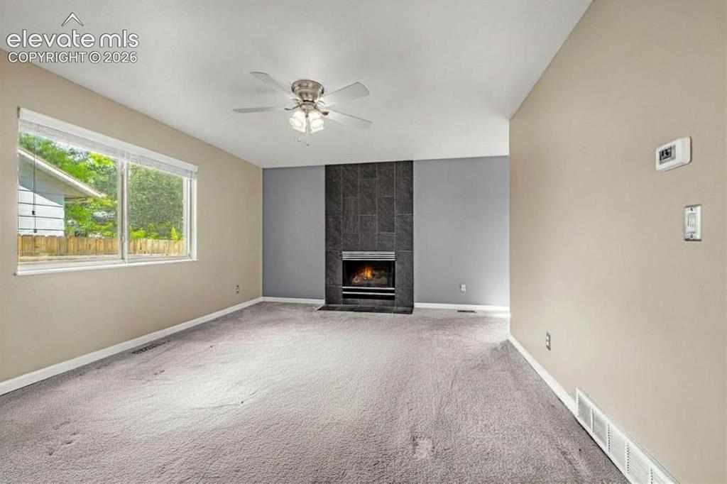 Image 43 of 49: Living area featuring a modern tile fireplace with a hearth, neutral wall t