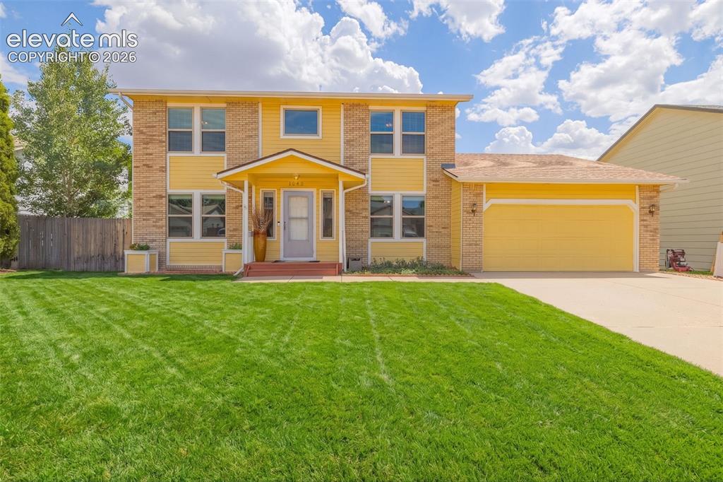 Image 7 of 49: Two-story residential exterior featuring yellow siding and brick accents